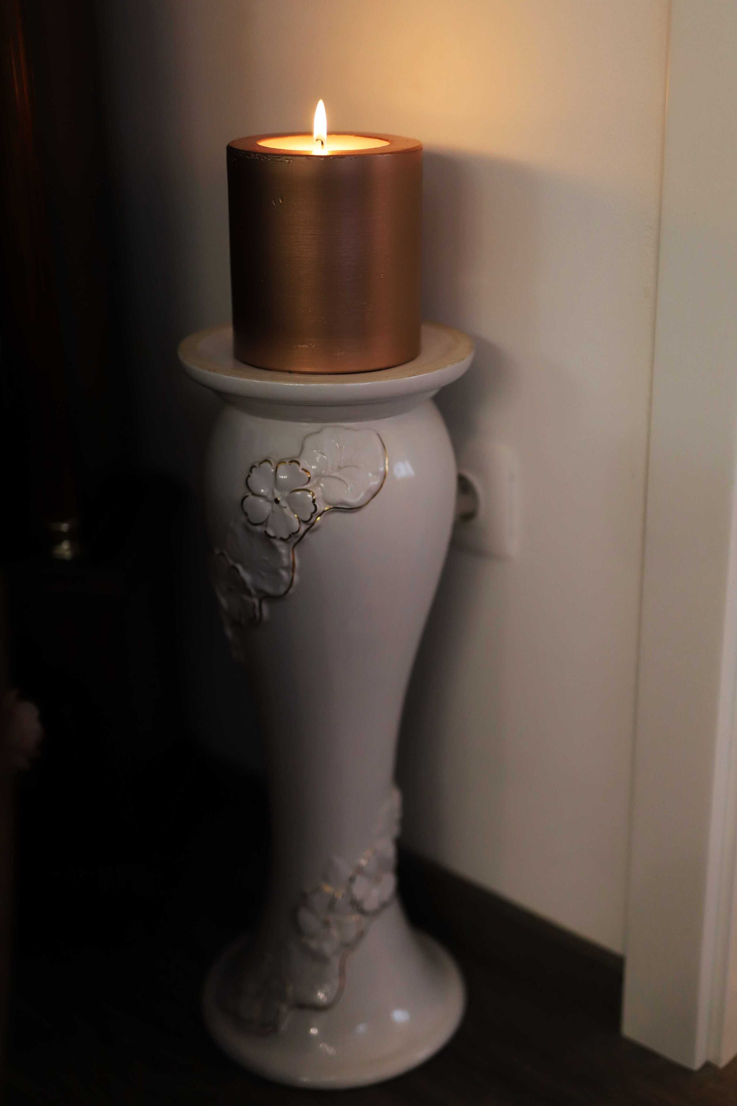 A white pedestal with a candle on top.