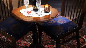 Una mesa de comedor con una botella de champán, dos copas y una vela sobre un posavasos de encaje.
