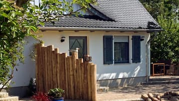 Ein Haus mit schrägem Dach, einem Holzzaun und einem steinbelagten Weg zum Eingang.