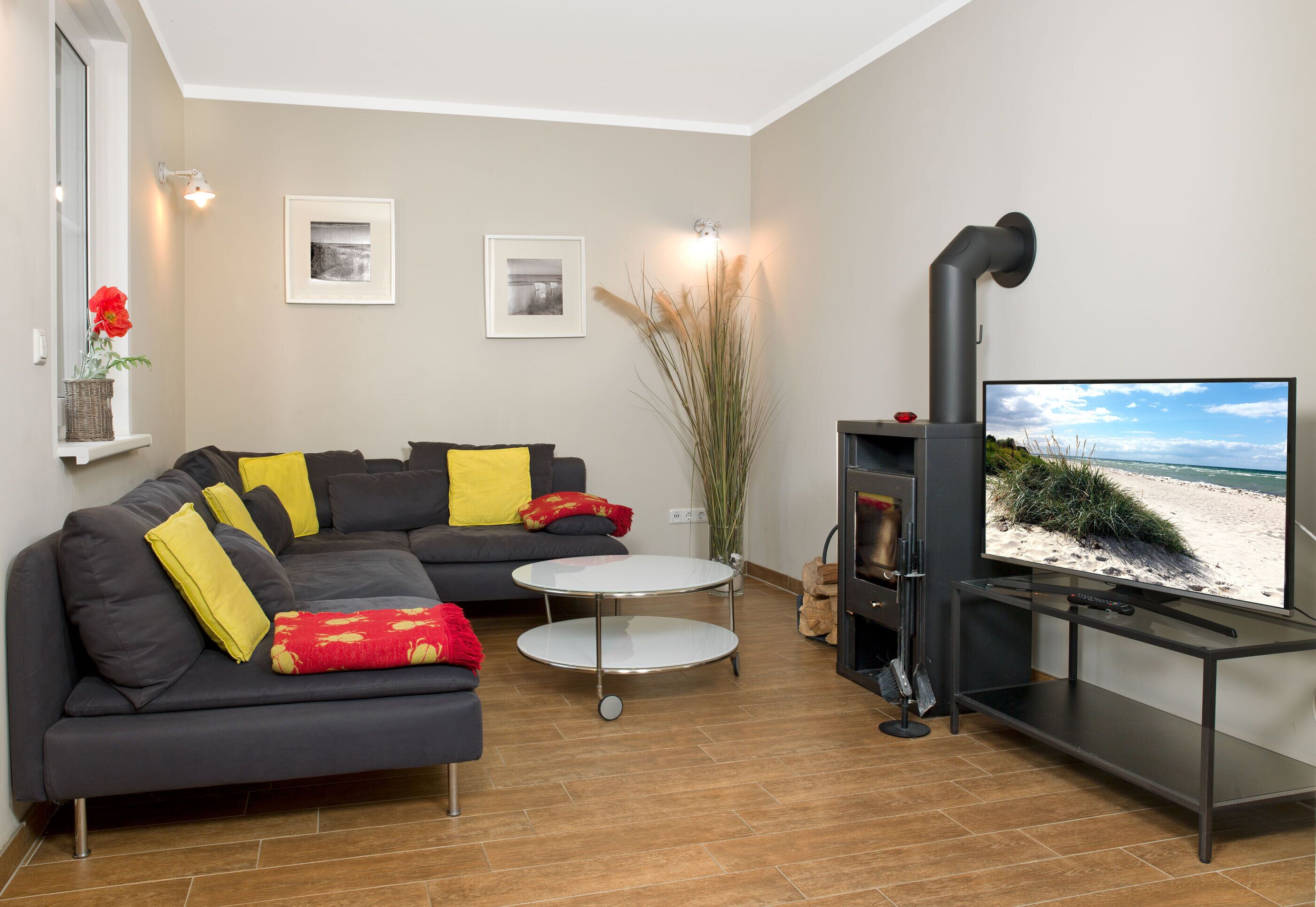 Uma sala de estar moderna com um sofá em forma de L, uma mesinha redonda, uma lareira e uma televisão.