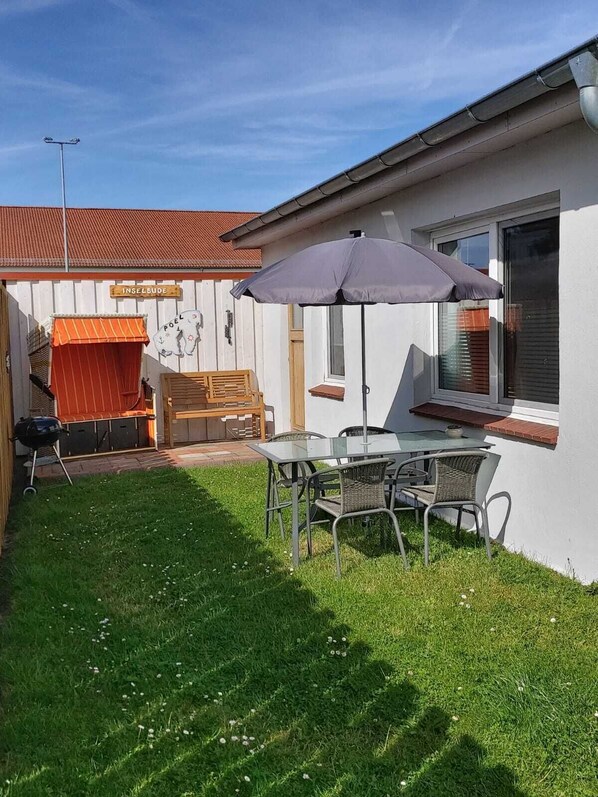 A patio area with a table and chairs, a barbecue grill, and a covered seating area. - Apt. (Insel Poel / OT Kirchdorf)