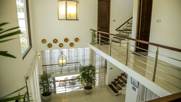A multi-level interior with a staircase, potted plants, and a hanging light fixture. - Villa Upper Dickson (Galle)
