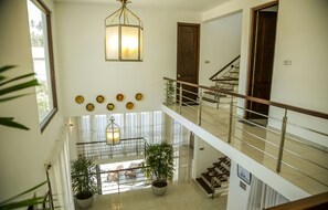 A multi-level interior with a staircase, potted plants, and a hanging light fixture. - Villa Upper Dickson (Galle)
