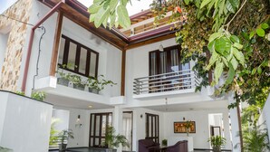 A modern two-story building with a spacious lobby, large windows, and multiple potted plants. - Villa Upper Dickson (Galle)