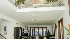 A spacious dining area with a high ceiling and a view of the kitchen and living area. - Villa Upper Dickson (Galle)