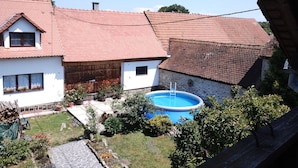 A house with a red-tiled roof, a swimming pool, and a garden.