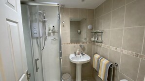 Une salle de bain moderne avec une douche à parois de verre, un lavabo sur colonne et des toilettes.