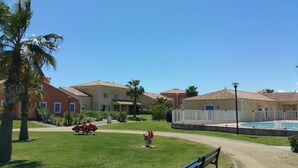 Una zona residenziale con diverse case, una piscina e un'area giochi con un'auto rossa e un idrante.