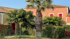 Un quartier résidentiel avec une maison en briques rouges, un palmier et une cour clôturée.