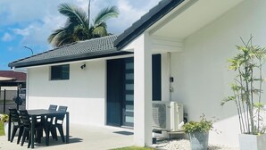 A modern house with a patio, a dining table, and chairs.