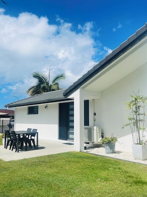 A modern house with a patio, a dining table, and chairs.
