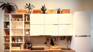 A compact kitchen with white cabinets, a wooden countertop, and a dining table. - Loft in Florence/Boboli with reserved garage parking space (Firenze)