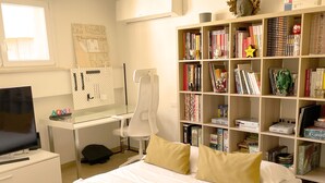 A hotel room with a large bed, a desk with a computer, a bookshelf, and a television. - Loft in Florence/Boboli with reserved garage parking space (Firenze)