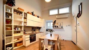 A modern kitchen with white cabinetry, a dining table with chairs, and a window above the sink. - Loft in Florence/Boboli with reserved garage parking space (Firenze)