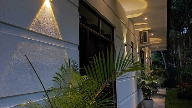 A modern building exterior with a pathway, potted plants, and outdoor lighting. - The most comfort rest starts here (Habaraduwa)