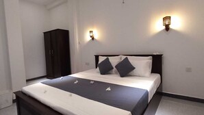 A modern hotel room with a large bed, dark wooden headboard, two wall-mounted lights, and a dark wardrobe. - The most comfort rest starts here (Habaraduwa)
