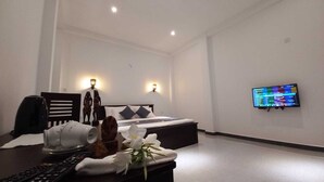 A hotel room with a bed, a TV mounted on the wall, a desk with a remote control, and decorative items. - The most comfort rest starts here (Habaraduwa)