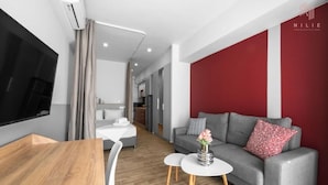 A modern living room with a grey sofa, a white coffee table, and a wooden dining table. - Big Apple 6 Nilie Hospitality MGMT (Thessaloniki)