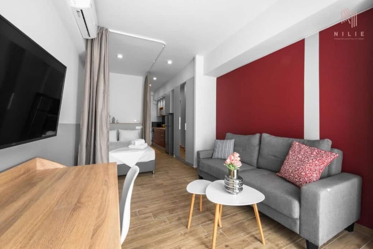 A modern living room with a grey sofa, a white coffee table, and a wooden dining table.