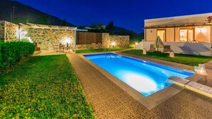 Une piscine avec un mur en pierre et un bâtiment moderne en arrière-plan.