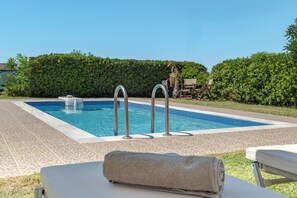 Una piscina rectangular con superficie de agua azul cristalina, rodeada por una solana con baldosas.