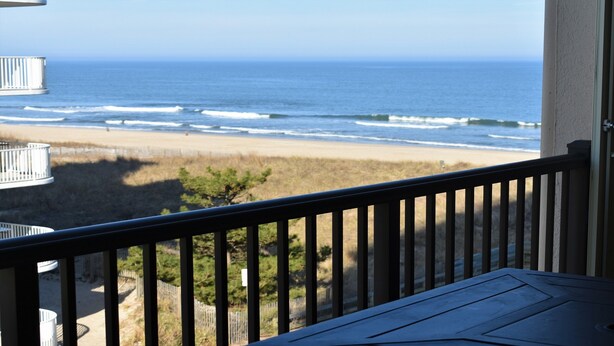 A balcony with a view of the beach and ocean.