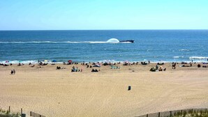 A beach with people, umbrellas, and a boat in the water.