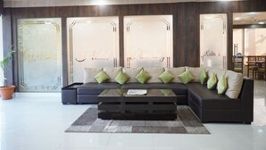 En moderne hotellobby med en modulsofa, et glasbord og en potteplante.