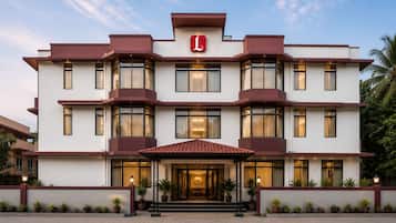 Ein mehrstöckiges Hotel mit markanter Rot-Weiß-Farbgebung, das einen großen Eingangsbereich mit einem geflasten Dach und Pflanzkübeln zeigt.