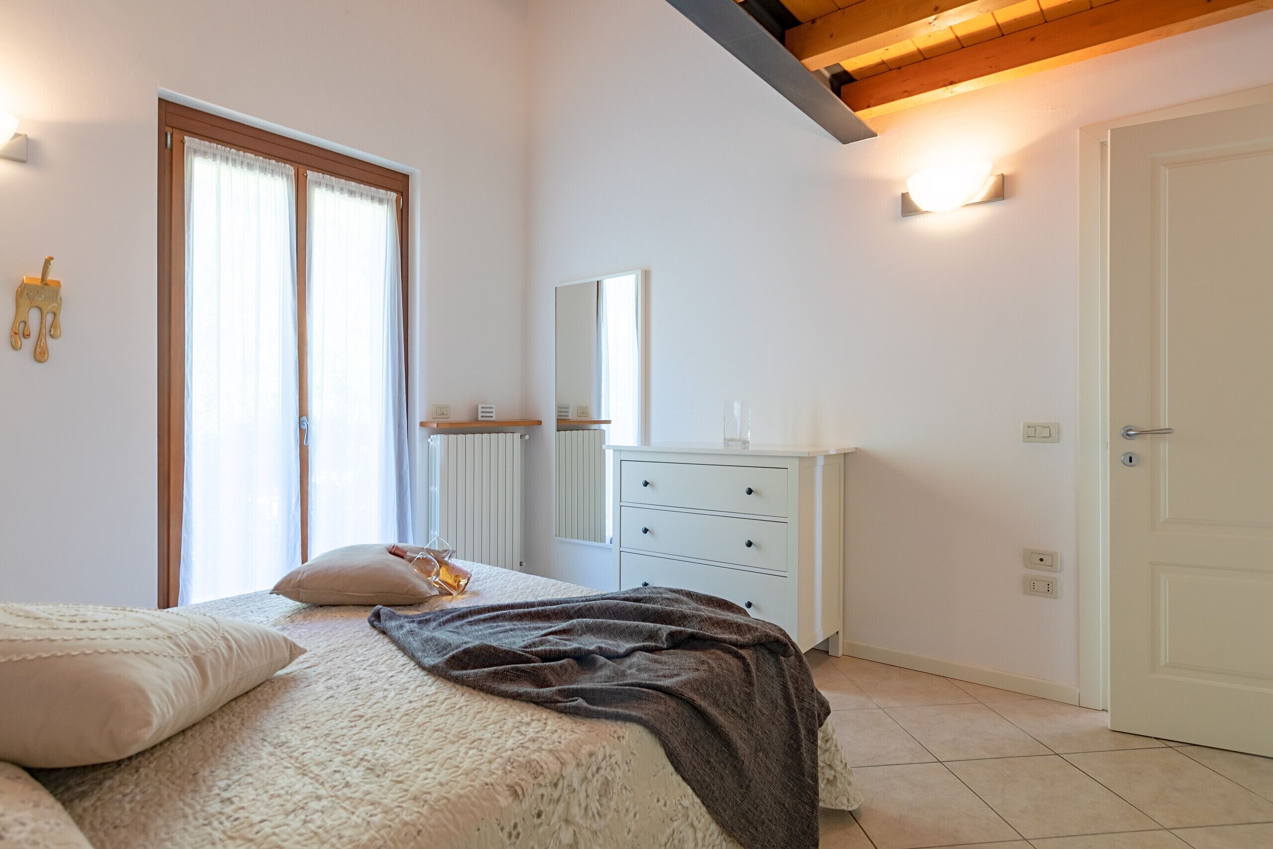 Une chambre à coucher avec un lit, une commode, un miroir et une porte.