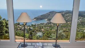 A room with a large window overlooking a coastal landscape, two table lamps, and a glass table. - Spectacular Villa with sea views.Begur. (Begur)