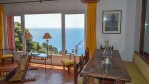 A dining area with a view of the sea, a table with chairs, and a lamp. - Spectacular Villa with sea views.Begur. (Begur)