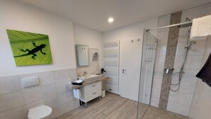 Moderni kylpyhuone, jossa on wc, pesuallas, peili ja suihku.