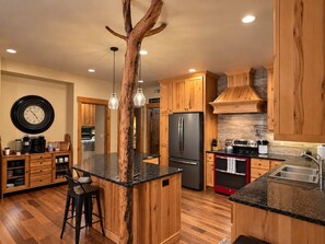 A kitchen with wooden cabinets, a central island, stainless steel appliances, and pendant lighting.