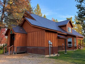 Eine Holzhütte mit einem Metall-Dach, einer Veranda und einem kleinen angebauten Schuppen.