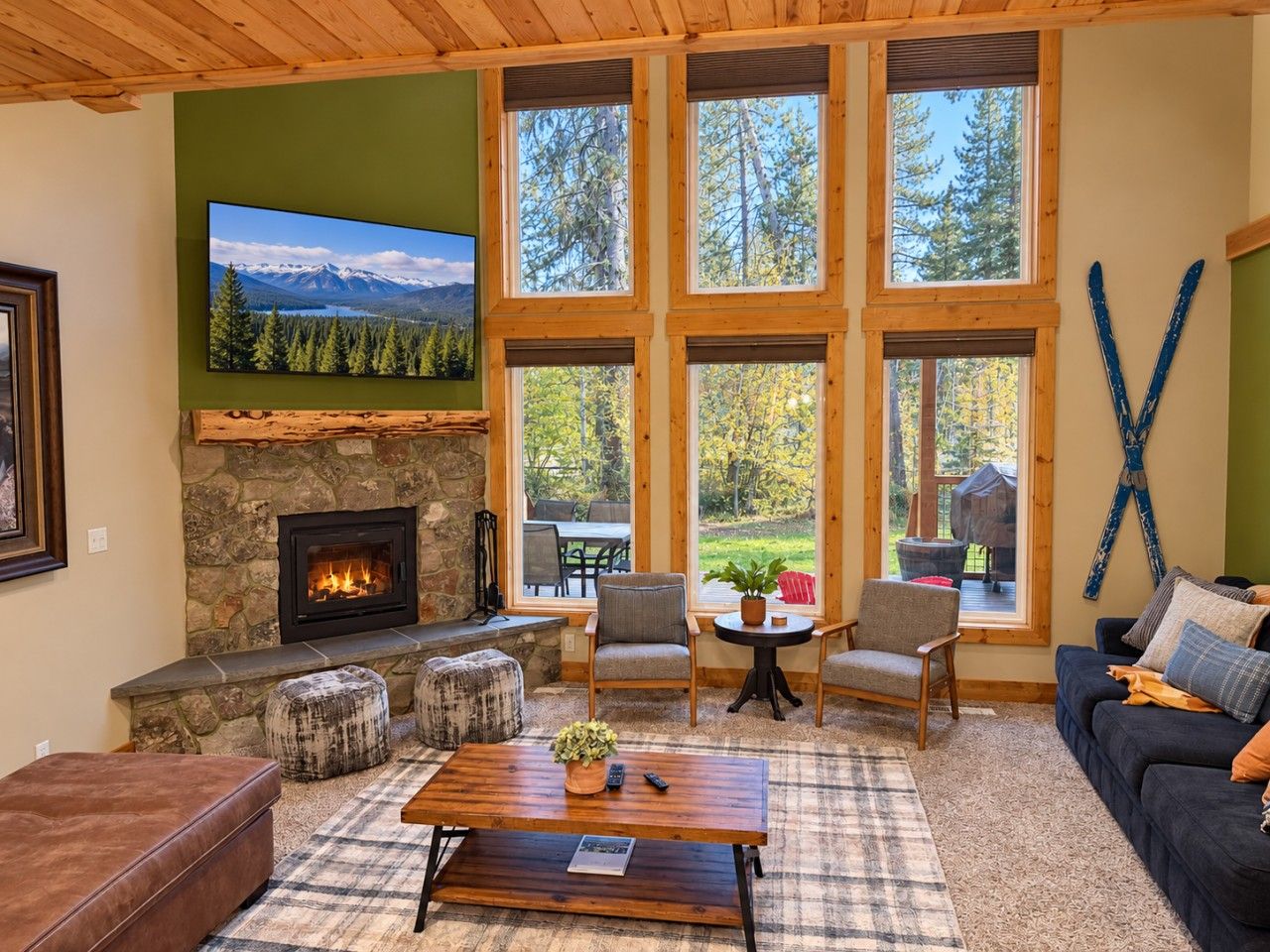 A cozy living room with a stone fireplace, large windows, and comfortable seating.