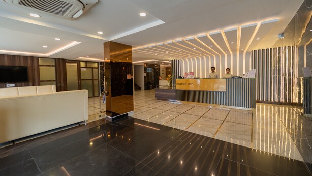 En moderne hotellobby med reception, siddeområde og stort fladskærms-tv.