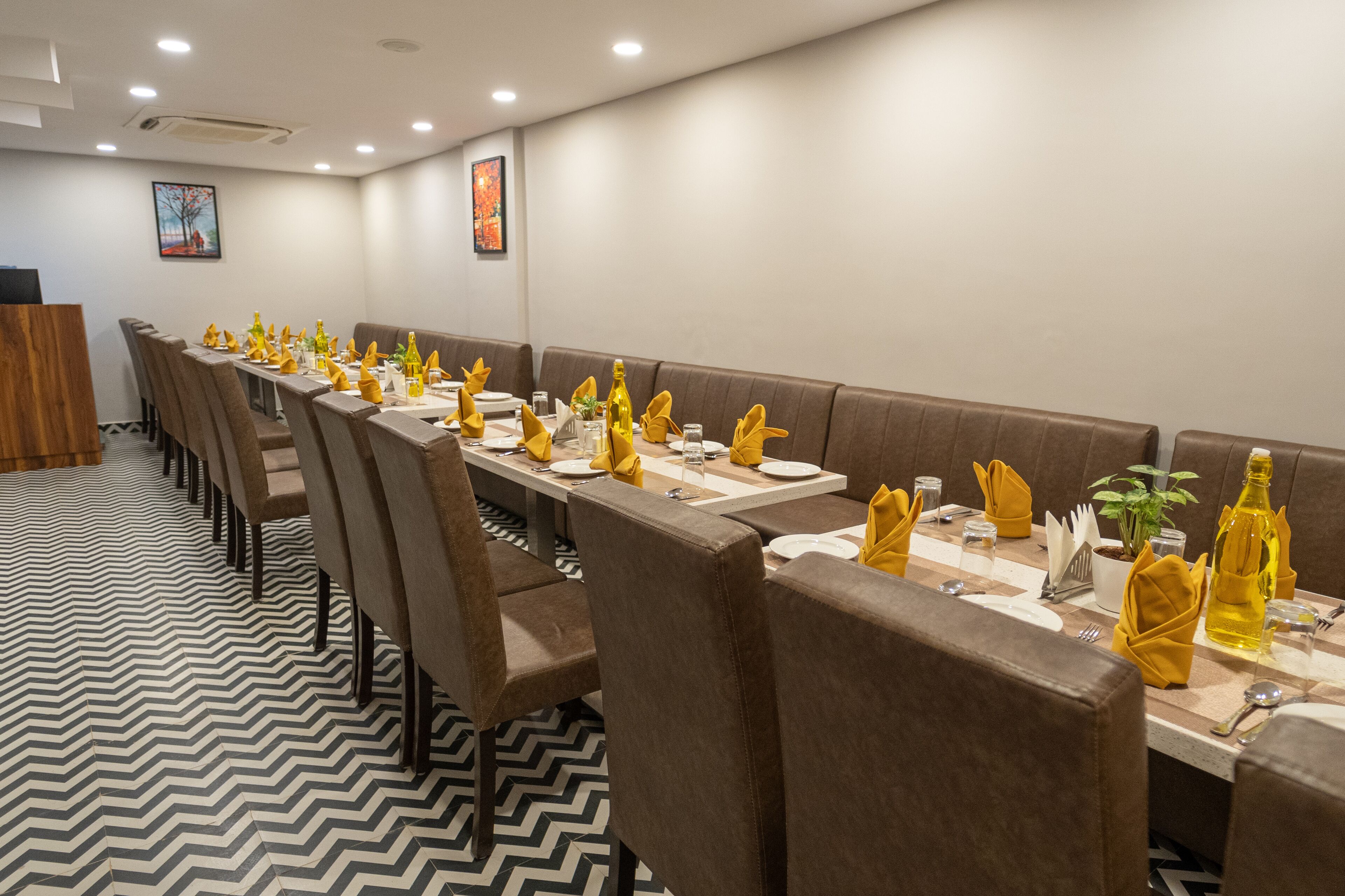 A conference room with long tables, brown upholstered booths, and a patterned floor.