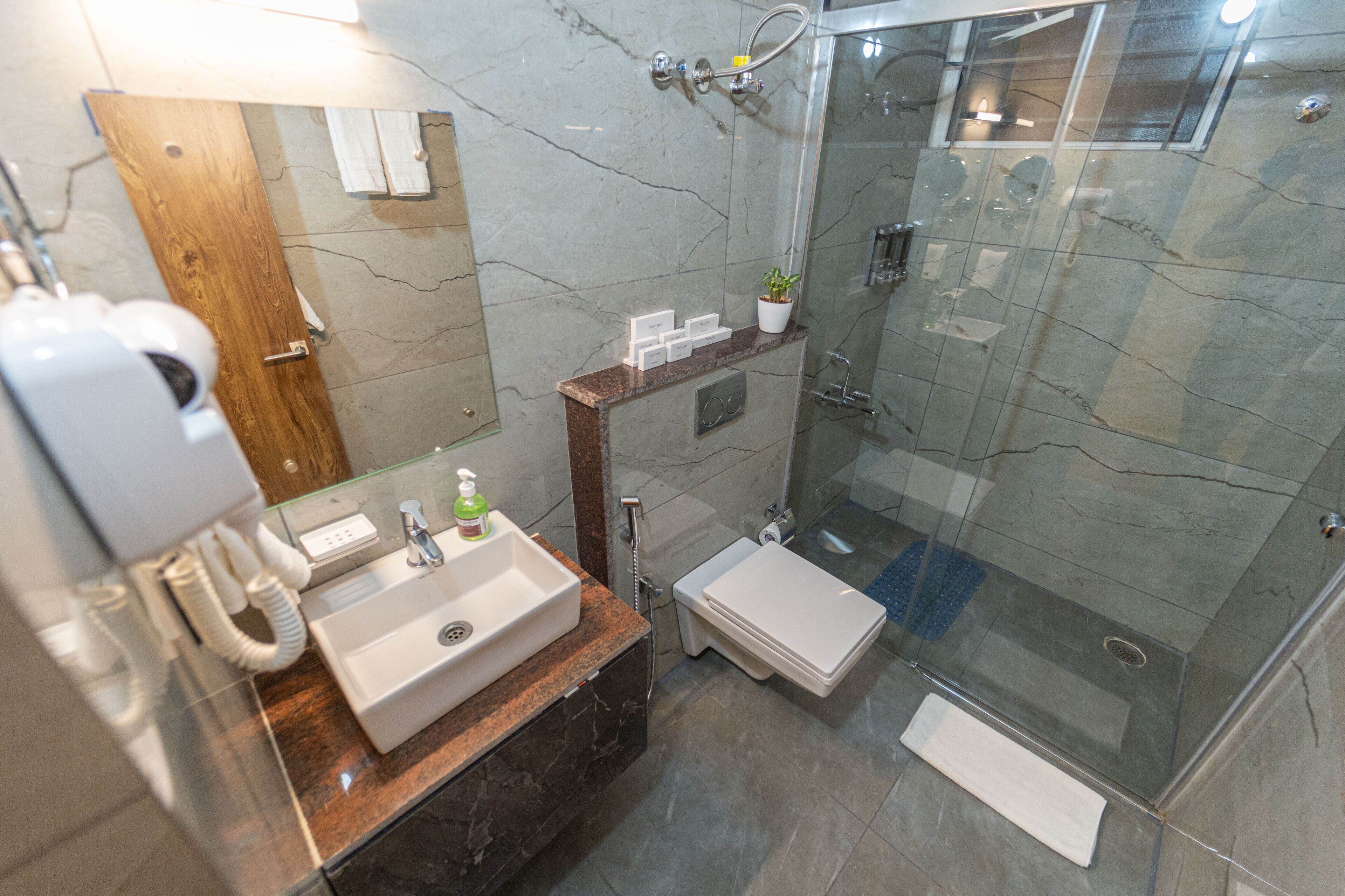 Ein modernes Badezimmer mit Marmorwaschbecken, einer Duschkabine aus Glas und einem Holzwaschtisch.