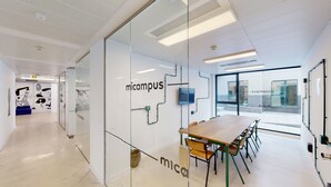 Une salle de conférence moderne avec des murs en verre, une table en bois et des chaises.