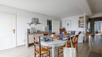 Un coin repas avec une table ronde, des chaises et une cuisine en arrière-plan.