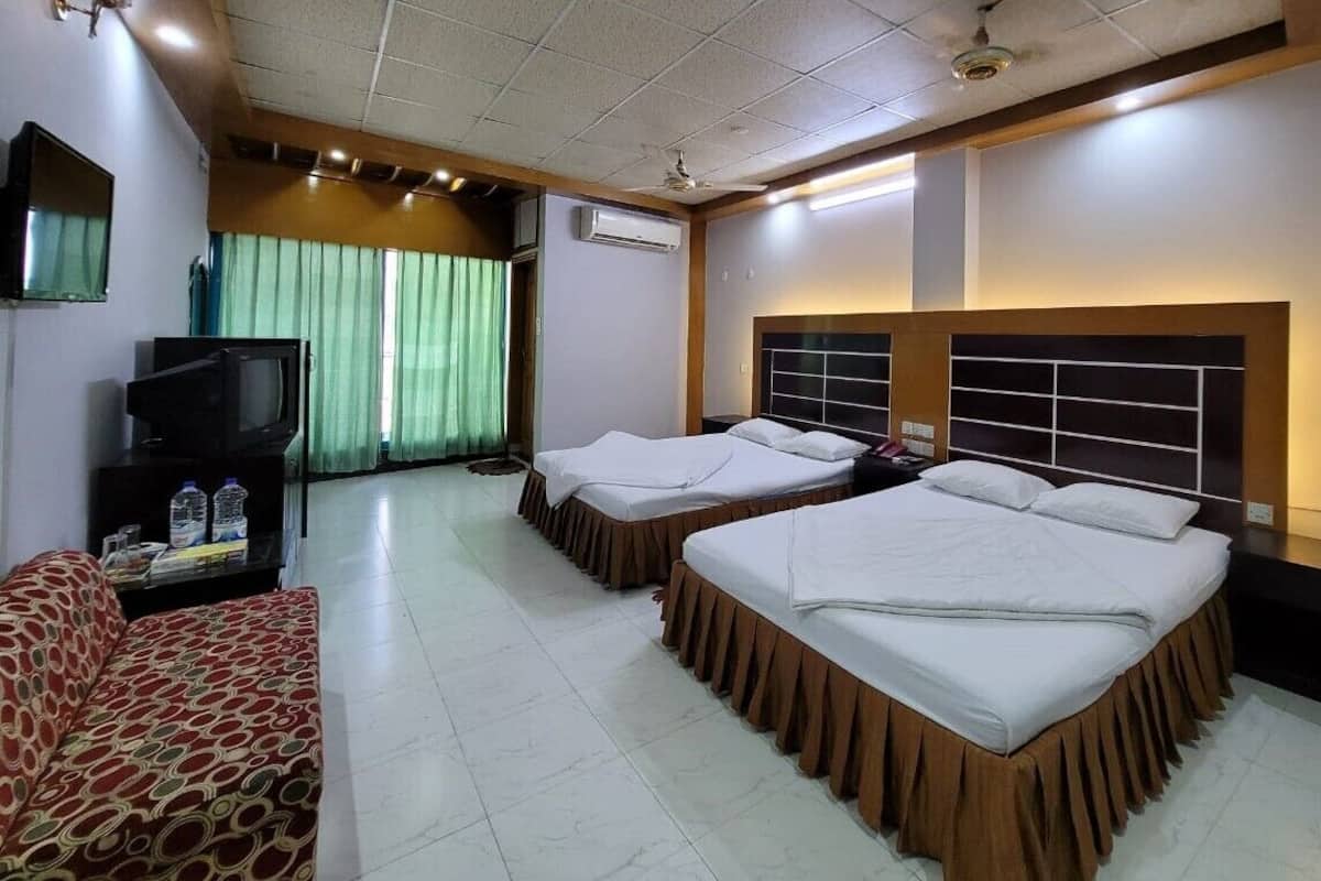 Une chambre d’hôtel avec deux lits, un canapé, une télévision et un appareil de climatisation.