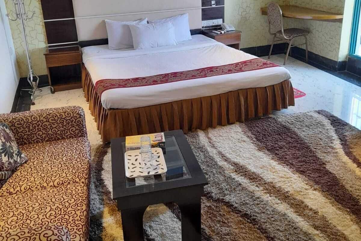 Une chambre d’hôtel avec un grand lit, un petit bureau, une chaise, un canapé et une table basse.