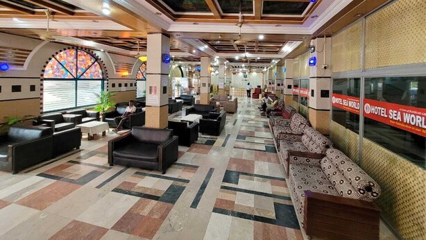A hotel lobby with a check-in counter, seating areas, and a large window with a stained glass design. - Hotel Sea World Cox's Bazar (Cox's Bazar)