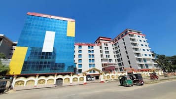 A hotel with a modern glass facade, a traditional building with a red roof, and a decorative entrance.