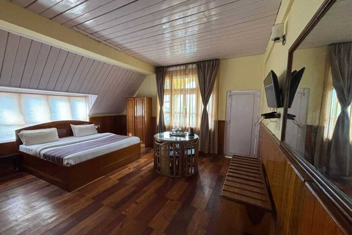 Un dormitorio con cama, una mesa redonda y un espejo grande.