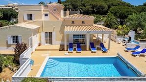 Un hotel con piscina, tumbonas y un patio cubierto.