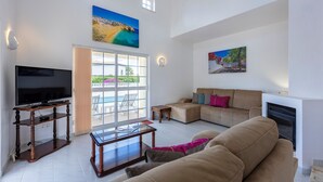Un amplio salón con televisión de pantalla plana, una mesa de centro, un sofá y una chimenea.