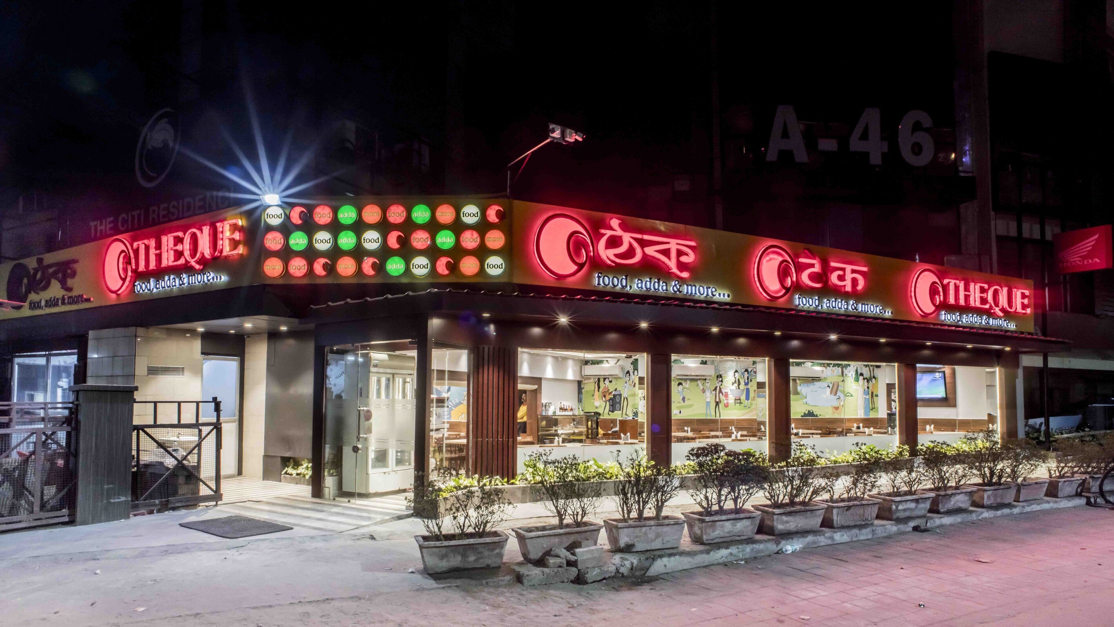 A restaurant with a sign that reads "THEQUE" and "food, adda & more..." with illuminated buttons indicating different food options.