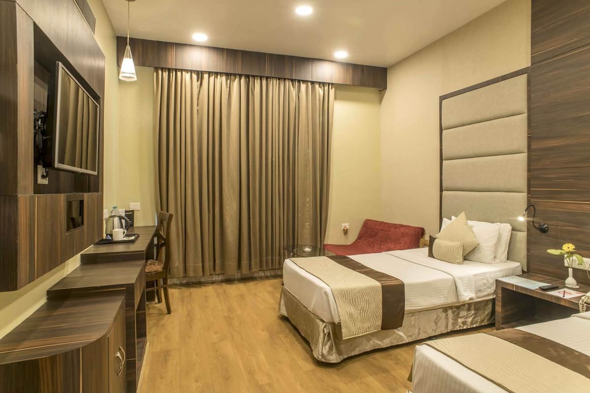 Quarto de hotel com cama, mesa de cabeceira, luminária e escrivaninha com cadeira.